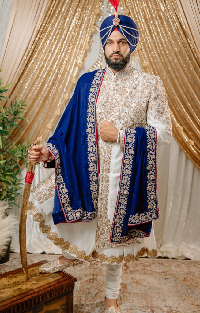 Sikh groom in an ivory sherwani with a maroon pag at his Anand Karaj