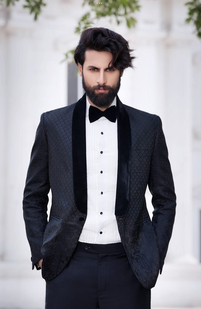 Groom in a black jacquard tuxedo with a velvet shawl lapel and bow tie, dressed for an evening reception